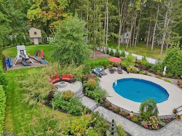 outdoor pool with a patio area, a lawn, and a fire pit