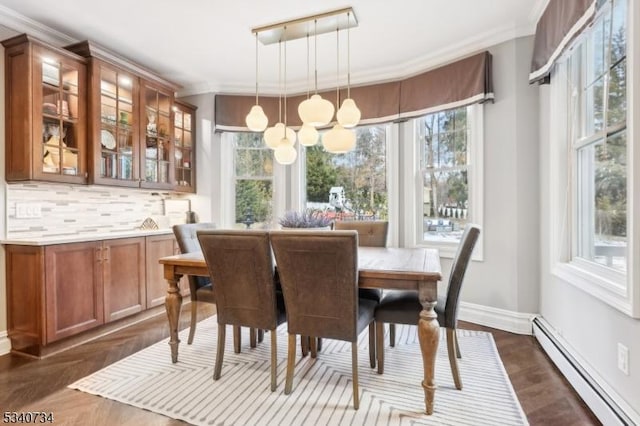 dining room featuring a baseboard heating unit, a wealth of natural light, ornamental molding, and baseboards