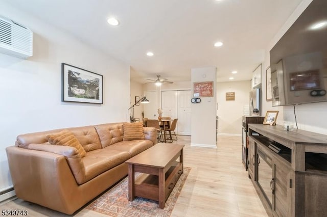 living room with baseboards, a ceiling fan, an AC wall unit, light wood-style floors, and recessed lighting