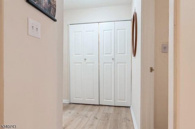 hall with baseboards and light wood-style floors