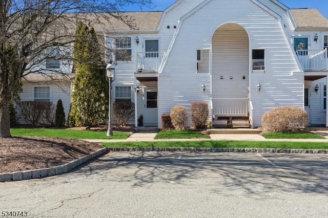 view of front of house with a balcony and a gambrel roof