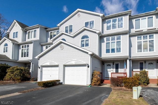 view of property with driveway, a garage, and a porch