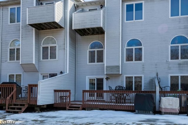 snow covered rear of property featuring a wooden deck