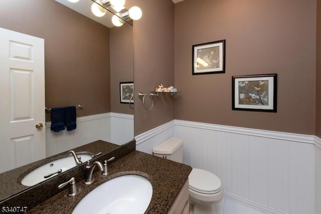 bathroom with a wainscoted wall, vanity, and toilet