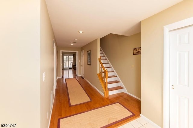 corridor with recessed lighting, wood finished floors, baseboards, and stairs