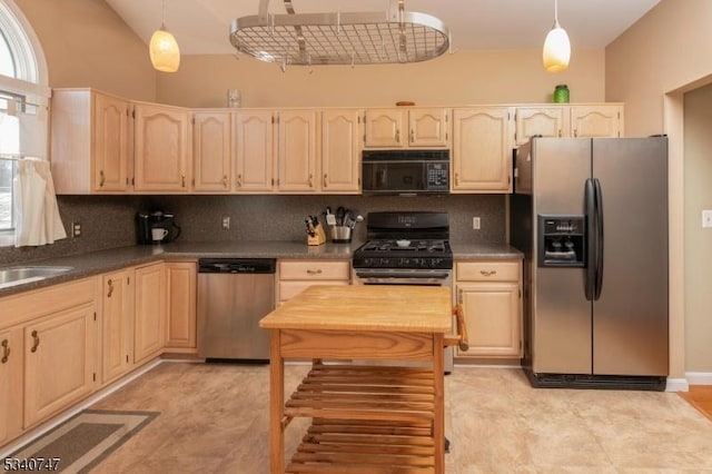 kitchen with stainless steel appliances, dark countertops, backsplash, and light brown cabinetry