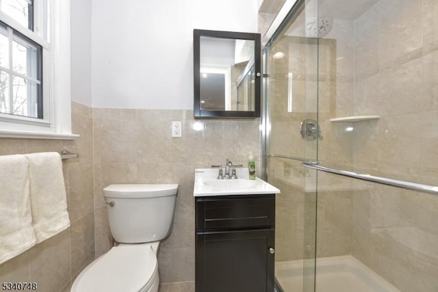 bathroom featuring a stall shower, tile walls, vanity, and toilet