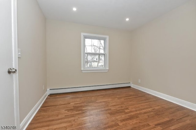 spare room featuring baseboards, a baseboard heating unit, wood finished floors, and recessed lighting