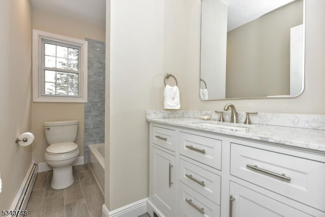 bathroom featuring toilet, baseboards, a baseboard heating unit, and vanity