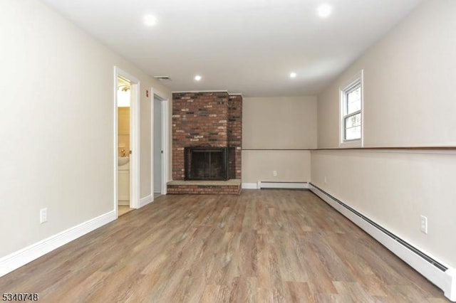 unfurnished living room with baseboards, wood finished floors, a brick fireplace, a baseboard heating unit, and recessed lighting