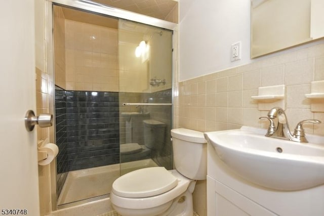 full bath with a stall shower, vanity, toilet, and tile walls