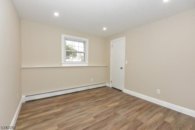 spare room featuring a baseboard radiator, recessed lighting, baseboards, and wood finished floors