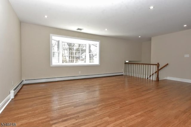 unfurnished room featuring recessed lighting, a baseboard heating unit, wood finished floors, visible vents, and baseboards