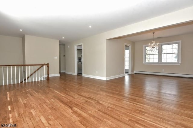 spare room with light wood-style floors, baseboards, baseboard heating, and an inviting chandelier