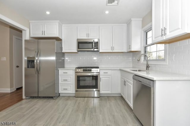 kitchen featuring stainless steel appliances, light countertops, visible vents, white cabinetry, and a sink