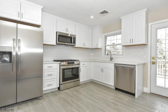 kitchen featuring a sink, visible vents, white cabinetry, light countertops, and appliances with stainless steel finishes