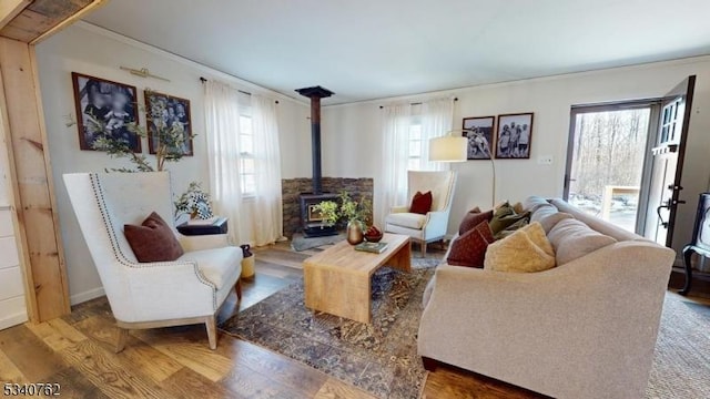 living area with a wood stove, ornamental molding, and wood finished floors