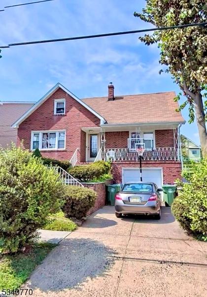 view of front of home featuring a garage, brick siding, driveway, and a chimney