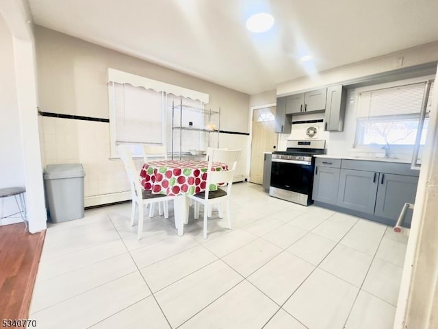 kitchen with light tile patterned floors, a sink, electric stove, light countertops, and gray cabinets