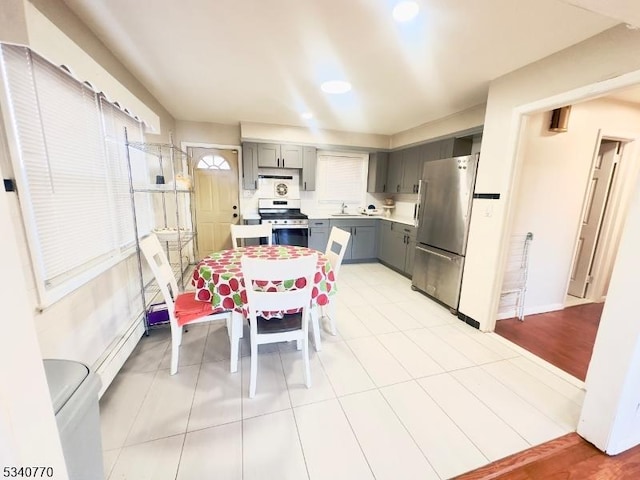 kitchen featuring a baseboard radiator, appliances with stainless steel finishes, gray cabinets, light countertops, and a sink