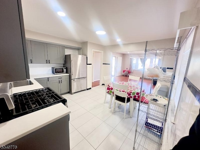 kitchen with light tile patterned flooring, stainless steel appliances, light countertops, and gray cabinetry