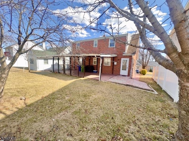 back of house featuring a patio area, fence, a lawn, and brick siding