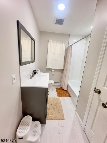 bathroom with visible vents, toilet, shower / bath combo with shower curtain, vanity, and a baseboard heating unit