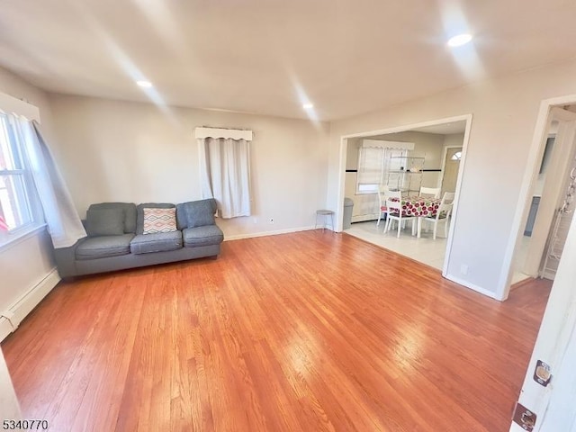 unfurnished living room featuring a baseboard radiator, recessed lighting, baseboards, and wood finished floors