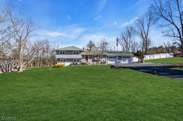 view of front of home with a garage, a front lawn, fence, and aphalt driveway