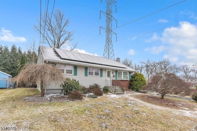 single story home featuring solar panels and a chimney