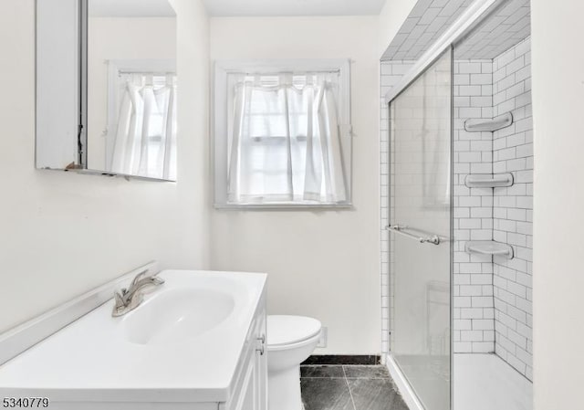 bathroom with toilet, a stall shower, vanity, tile patterned flooring, and baseboards