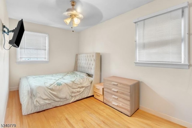 bedroom featuring a ceiling fan, baseboards, and wood finished floors