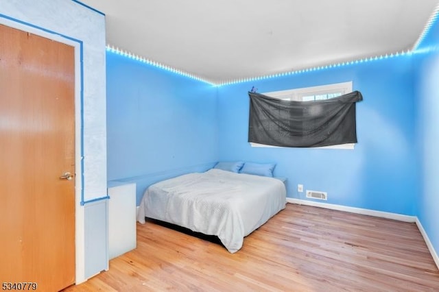 bedroom featuring baseboards, visible vents, and wood finished floors