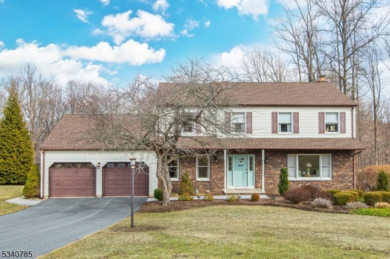 traditional-style home with a garage, driveway, a front lawn, and brick siding