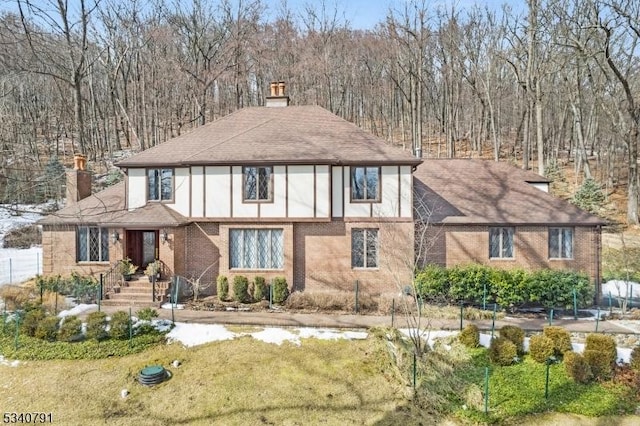 english style home with a chimney and brick siding