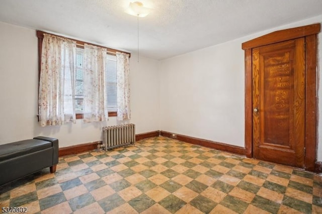 spare room featuring tile patterned floors, radiator, and baseboards