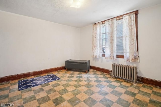 empty room featuring radiator, a textured ceiling, and baseboards