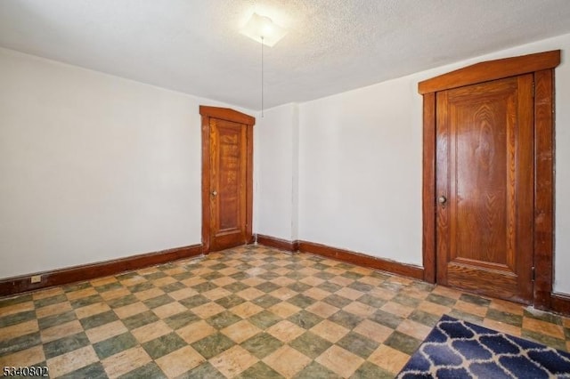 empty room with tile patterned floors, baseboards, and a textured ceiling