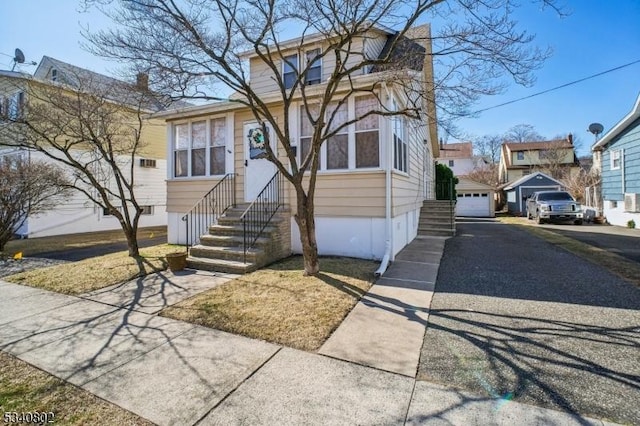 view of front of house featuring aphalt driveway, a residential view, an outdoor structure, and entry steps