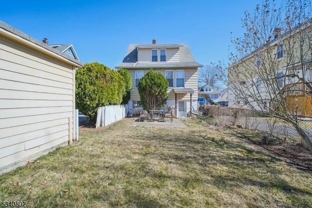 rear view of property featuring a yard, a chimney, a patio, and fence