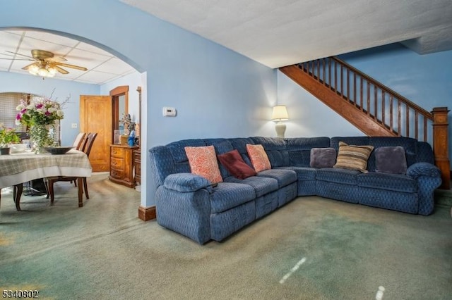 living room with stairway, arched walkways, carpet floors, and ceiling fan