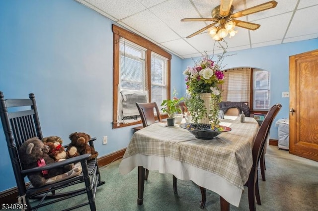 carpeted dining room featuring a paneled ceiling, baseboards, and ceiling fan