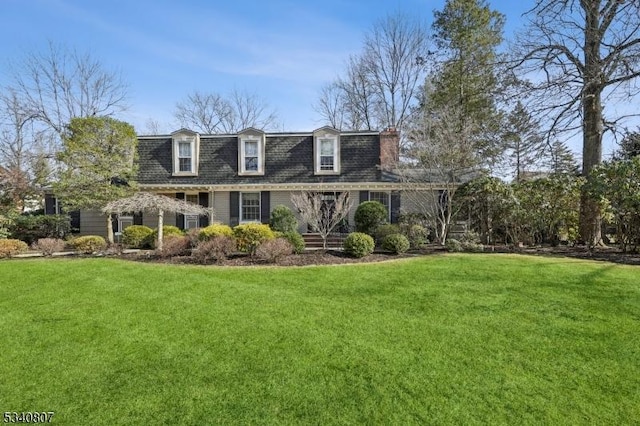 view of front of property with mansard roof, a front yard, and a shingled roof