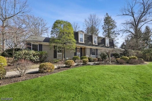 view of front of house featuring a front lawn, mansard roof, a shingled roof, and brick siding