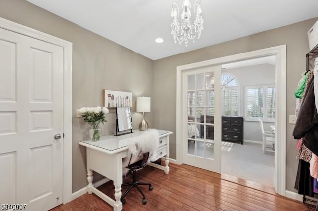 office area with baseboards, wood-type flooring, and an inviting chandelier