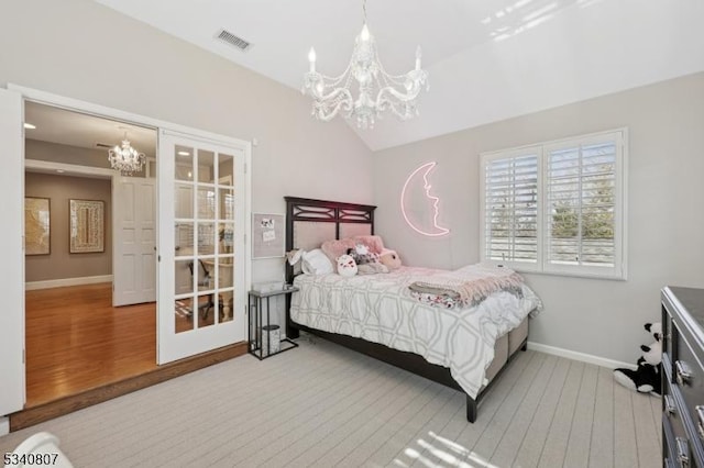 bedroom featuring lofted ceiling, wood finished floors, visible vents, baseboards, and an inviting chandelier