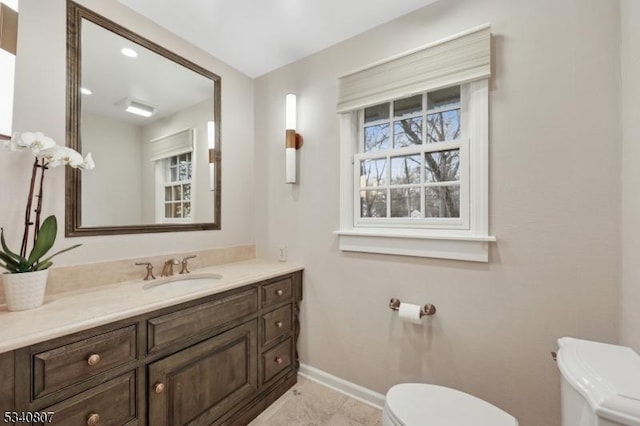 half bath with toilet, baseboards, and vanity