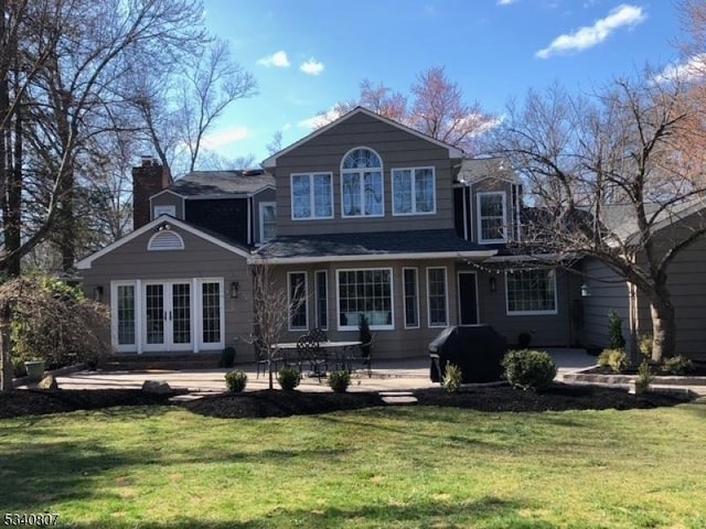 back of property with french doors, a yard, a chimney, and a patio