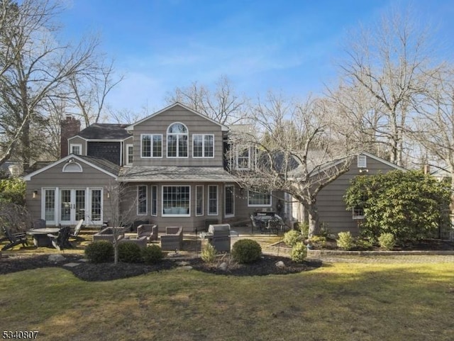 rear view of property featuring french doors, a yard, a chimney, a patio, and a fire pit