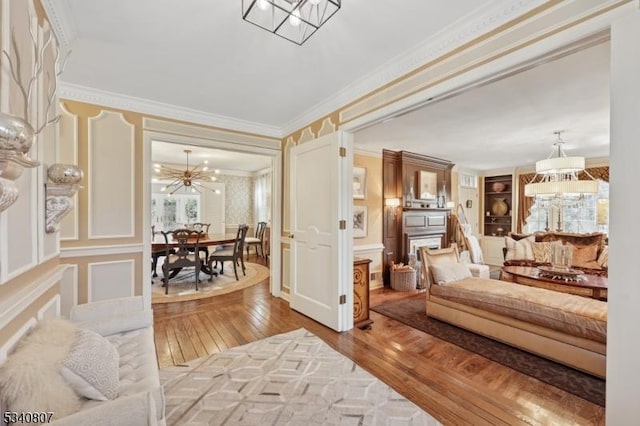 interior space featuring a chandelier, a decorative wall, wood-type flooring, and crown molding